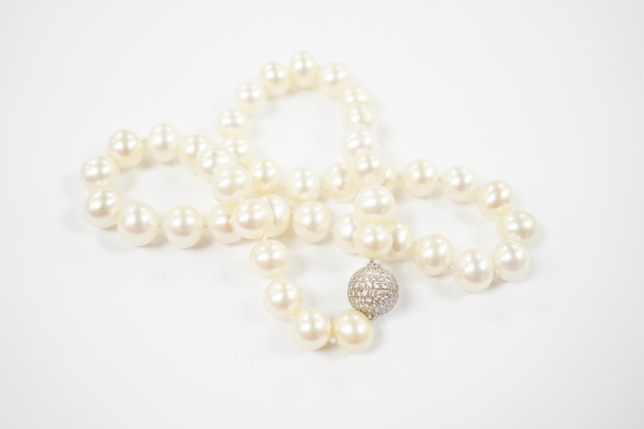 A modern single strand cultured pearl necklace with pave set diamond mounted spherical yellow metal clasp, 44cm.